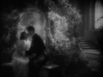 Movie still from “Lady for a Day” (1933), directed by Frank Capra – A black - and - white photo of a man and a woman kissing; Wide shot, High angle