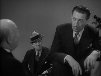 Movie still from “Lady for a Day” (1933), directed by Frank Capra – A man in a suit and a hat sitting next to another man in a suit; Medium shot, Low angle