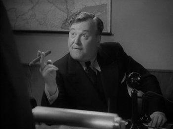 Movie still from “Lady for a Day” (1933), directed by Frank Capra – An older man sitting at a desk smoking a cigarette; Close Up shot, Low angle