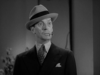 Movie still from “Lady for a Day” (1933), directed by Frank Capra – A man in a suit and hat smoking a pipe; Close Up shot, Low angle