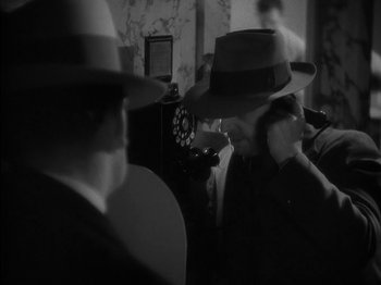 Movie still from “Lady for a Day” (1933), directed by Frank Capra – A man in a hat is talking on the phone; Close Up shot, High angle