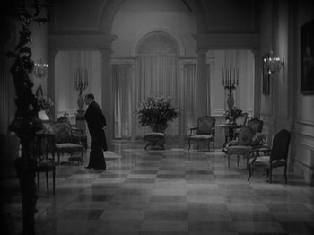 Movie still from “Lady for a Day” (1933), directed by Frank Capra – A man walking in a room filled with furniture; Extreme Wide shot, High angle