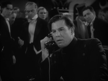 Movie still from “Lady for a Day” (1933), directed by Frank Capra – A man talking on a phone in front of a group of people; Medium shot, Low angle