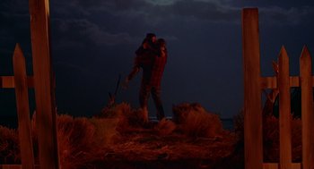Movie still from “Lady in White” (1988), directed by Frank LaLoggia – A man carrying a woman on his back in the dark; Wide shot, Low angle