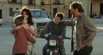 Movie still from “Everybody Knows” (2018), directed by Asghar Farhadi – A group of people standing next to each other on a motorcycle; Medium shot, Over the shoulder angle
