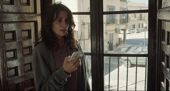 Movie still from “Everybody Knows” (2018), directed by Asghar Farhadi – A woman standing in front of a window holding a cell phone; Close Up shot, Over the shoulder angle