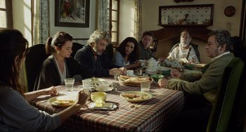 Movie still from “Everybody Knows” (2018), directed by Asghar Farhadi – A group of people sitting around a table eating food; Medium shot, Over the shoulder angle