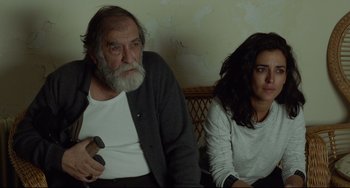 Movie still from “Everybody Knows” (2018), directed by Asghar Farhadi – An older man and a younger woman sitting next to each other; Medium shot, High angle