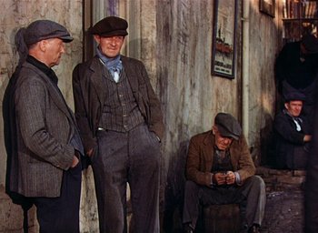 Movie still from “Lassie Come Home” (1943), directed by Fred M. Wilcox – A group of men standing next to each other on the street; Medium shot, Low angle