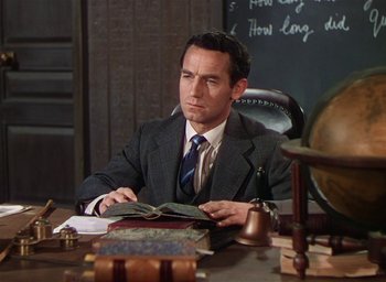 Movie still from “Lassie Come Home” (1943), directed by Fred M. Wilcox – A man sitting at a desk with a book in his hands; Medium shot, High angle