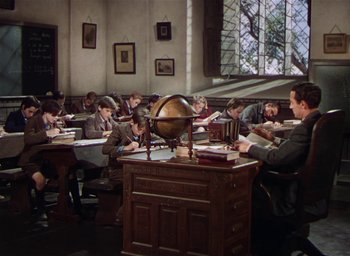 Movie still from “Lassie Come Home” (1943), directed by Fred M. Wilcox – A group of people sitting at a desk in a room; Wide shot, High angle