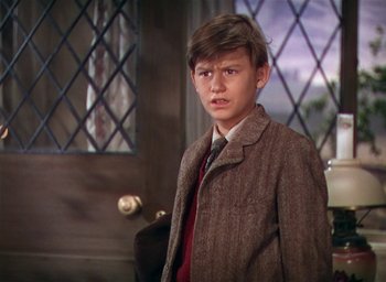 Movie still from “Lassie Come Home” (1943), directed by Fred M. Wilcox – A young boy wearing a suit and tie in front of a window; Medium shot, Low angle