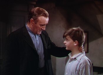 Movie still from “Lassie Come Home” (1943), directed by Fred M. Wilcox – An older man and a young boy standing next to each other; Medium shot, Low angle