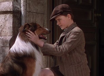 Movie still from “Lassie Come Home” (1943), directed by Fred M. Wilcox – A boy petting a dog on the ear of another dog; Close Up shot, High angle