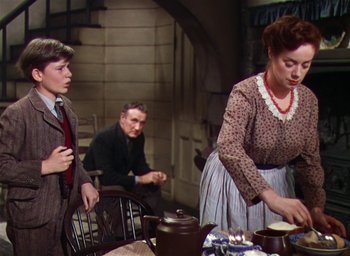Movie still from “Lassie Come Home” (1943), directed by Fred M. Wilcox – A man and a woman standing in front of a table; Medium shot, Low angle