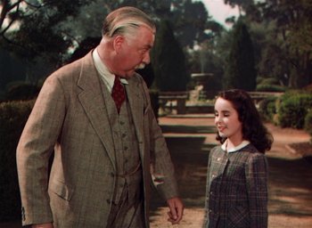 Movie still from “Lassie Come Home” (1943), directed by Fred M. Wilcox – An older man and a young girl are standing outside; Medium shot, Over the shoulder angle