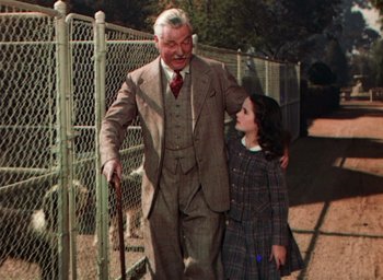Movie still from “Lassie Come Home” (1943), directed by Fred M. Wilcox – An older man and a young girl walking on a sidewalk; Medium shot, High angle