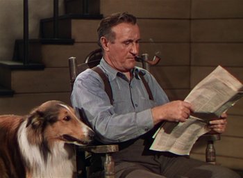 Movie still from “Lassie Come Home” (1943), directed by Fred M. Wilcox – A man sitting in a chair with a dog; Medium shot, High angle