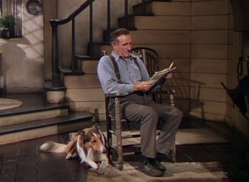Movie still from “Lassie Come Home” (1943), directed by Fred M. Wilcox – A man sitting in a rocking chair reading a newspaper; Wide shot, High angle