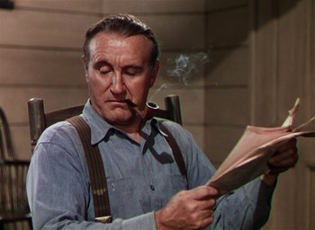 Movie still from “Lassie Come Home” (1943), directed by Fred M. Wilcox – An older man smoking a pipe while reading a book; Medium shot, Low angle