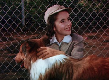 Movie still from “Lassie Come Home” (1943), directed by Fred M. Wilcox – A woman is hugging a dog behind a chain link fence; Close Up shot, High angle