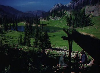 Movie still from “Lassie Come Home” (1943), directed by Fred M. Wilcox – A man sitting in the grass next to a lake; Wide shot, High angle