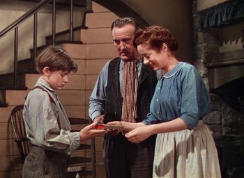 Movie still from “Lassie Come Home” (1943), directed by Fred M. Wilcox – A man and a woman and a young boy looking at a piece of paper; Medium shot, Low angle