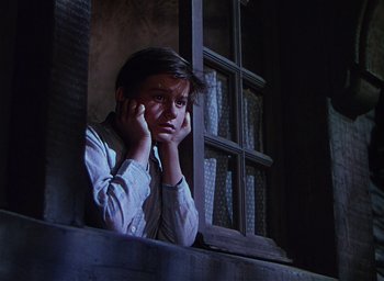 Movie still from “Lassie Come Home” (1943), directed by Fred M. Wilcox – A young boy sitting on a window ledge looking sad; Medium shot, Low angle