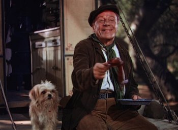 Movie still from “Lassie Come Home” (1943), directed by Fred M. Wilcox – An old man sitting next to a small white dog; Medium shot, Low angle