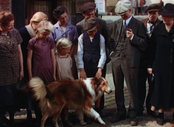 Movie still from “Lassie Come Home” (1943), directed by Fred M. Wilcox – A group of people standing around a brown and white dog; Wide shot, High angle
