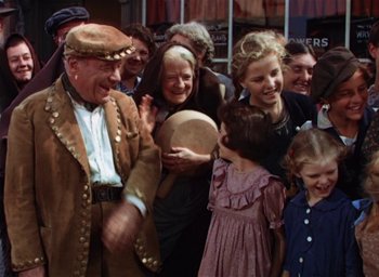 Movie still from “Lassie Come Home” (1943), directed by Fred M. Wilcox – An old man and a group of people in a crowd; Medium shot, Over the shoulder angle