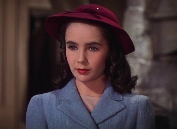 Movie still from “Lassie Come Home” (1943), directed by Fred M. Wilcox – A young woman wearing a red hat and a blue suit; Close Up shot, Over the shoulder angle
