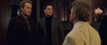 Movie still from “Last Chance Harvey” (2008), directed by Joel Hopkins – A man wearing a suit and tie standing next to two other men; Medium shot, Over the shoulder angle