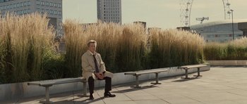 Movie still from “Last Chance Harvey” (2008), directed by Joel Hopkins – A man sitting on top of a bench in front of tall grass; Wide shot, High angle