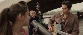 Movie still from “Last Chance Harvey” (2008), directed by Joel Hopkins – A group of people playing music on a bridge; Medium shot, Over the shoulder angle