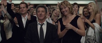 Movie still from “Last Chance Harvey” (2008), directed by Joel Hopkins – A man and a woman are standing in front of a group of people; Medium shot, Over the shoulder angle