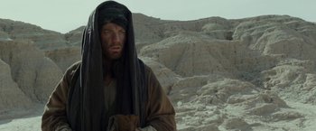 Movie still from “Last Days in the Desert” (2015), directed by Rodrigo García – A man with a beard wearing a black headscarf; Medium shot, Over the shoulder angle