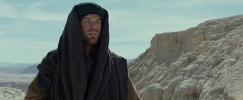 Movie still from “Last Days in the Desert” (2015), directed by Rodrigo García – A man with a beard and a black turban on; Medium shot, Low angle