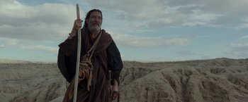 Movie still from “Last Days in the Desert” (2015), directed by Rodrigo García – An old man holding a stick standing in the desert; Medium shot, Low angle