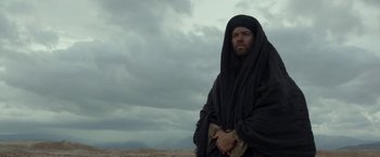 Movie still from “Last Days in the Desert” (2015), directed by Rodrigo García – A man with a beard wearing a black robe; Medium shot, Low angle