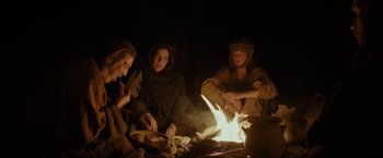 Movie still from “Last Days in the Desert” (2015), directed by Rodrigo García – A group of people sitting around a fire at night; Medium shot, Over the shoulder angle