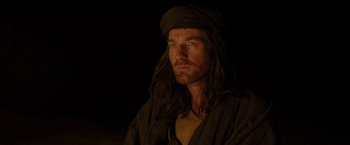 Movie still from “Last Days in the Desert” (2015), directed by Rodrigo García – A man with long black hair wearing a black turban; Close Up shot, Over the shoulder angle