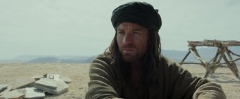 Movie still from “Last Days in the Desert” (2015), directed by Rodrigo García – A person with long hair wearing a turban; Close Up shot, Over the shoulder angle