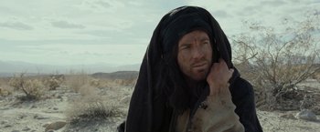 Movie still from “Last Days in the Desert” (2015), directed by Rodrigo García – A man with long black hair and a black headscarf; Close Up shot, Low angle