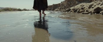 Movie still from “Last Days in the Desert” (2015), directed by Rodrigo García – A person walking on the beach in the water; Wide shot, High angle