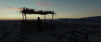 Movie still from “Last Days in the Desert” (2015), directed by Rodrigo García – A person standing on top of a hill near a tree; Wide shot, Low angle