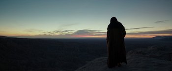 Movie still from “Last Days in the Desert” (2015), directed by Rodrigo García – A person standing on top of a mountain at dusk; Extreme Wide shot, Low angle