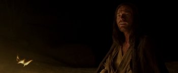 Movie still from “Last Days in the Desert” (2015), directed by Rodrigo García – A man with long hair and a beard sitting in a dark room; Close Up shot, Over the shoulder angle