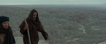 Movie still from “Last Days in the Desert” (2015), directed by Rodrigo García – A man standing on top of a mountain near a valley; Wide shot, Low angle