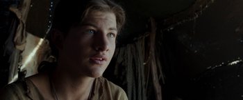 Movie still from “Last Days in the Desert” (2015), directed by Rodrigo García – A young man looking into the distance in a dark room; Close Up shot, Over the shoulder angle